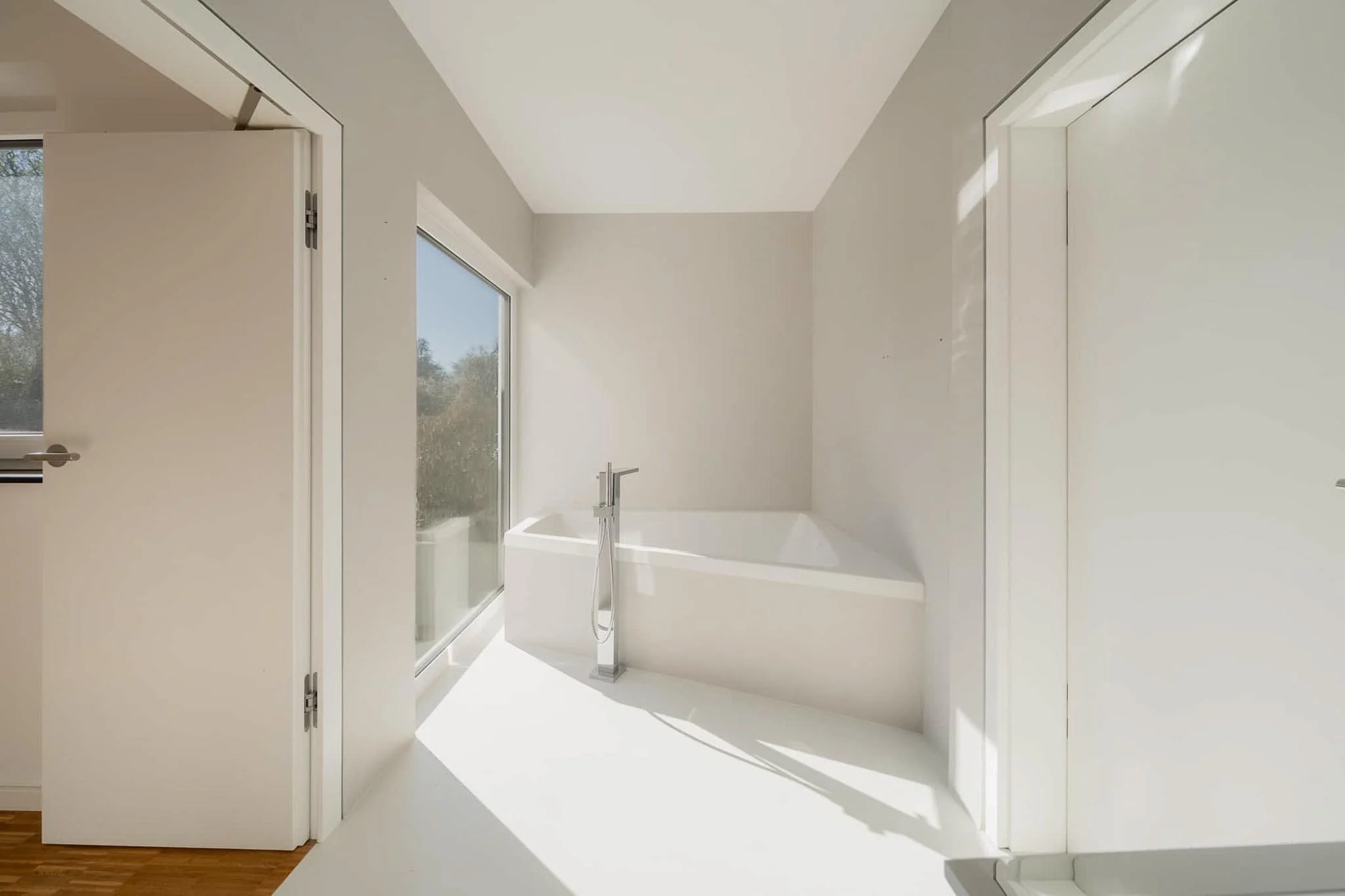 Helles Bad mit freistehender Wanne und bodentiefem Fenster zum Garten — Immobilienfotografie Maurice Veith