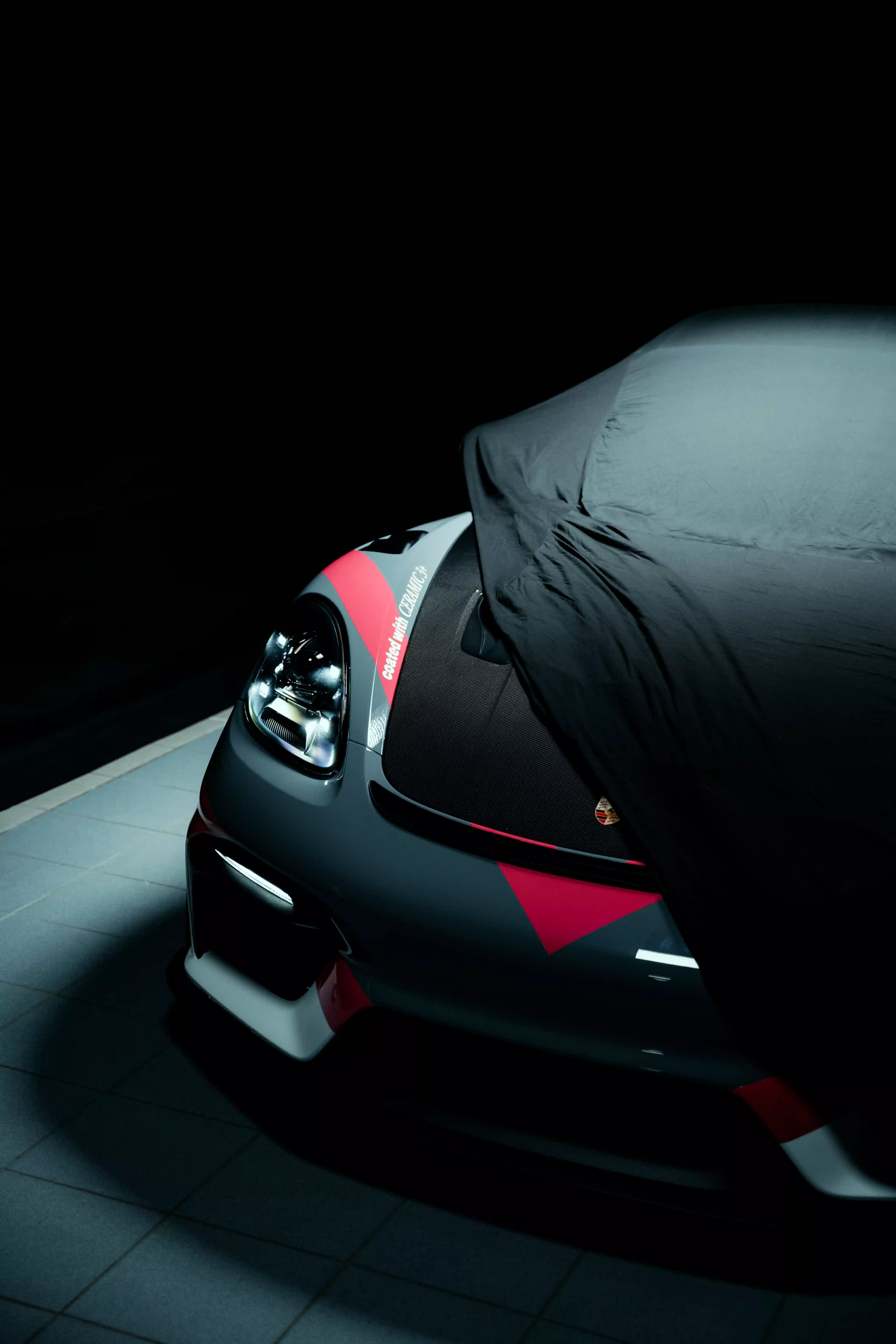 Porsche im Studio teils unter Abdeckung mit beleuchtetem Frontscheinwerfer — Automobilfotografie Maurice Veith