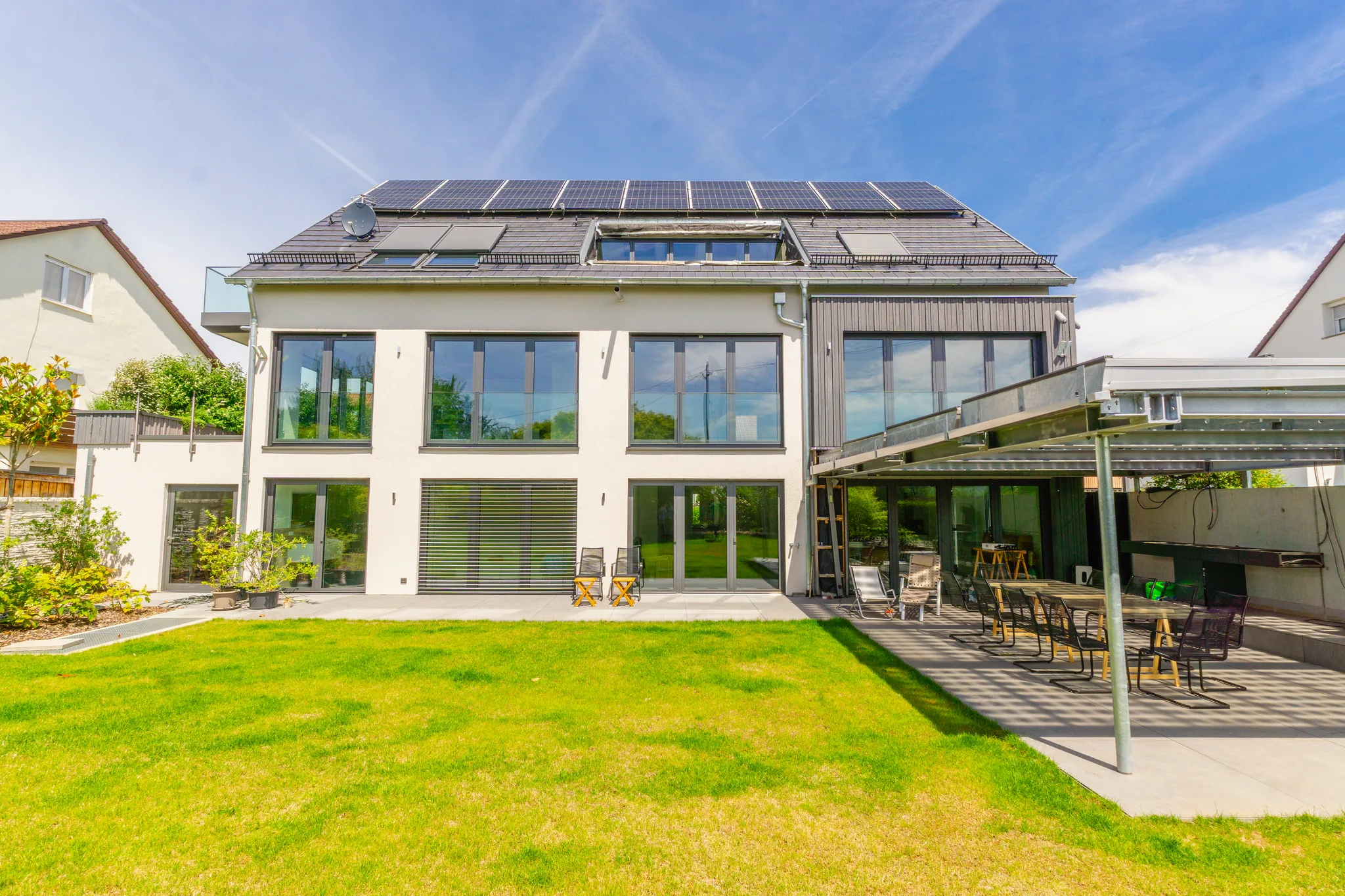 Gartenseite des Neubaus mit Rasen, Terrassen und Solardach – Fellbach