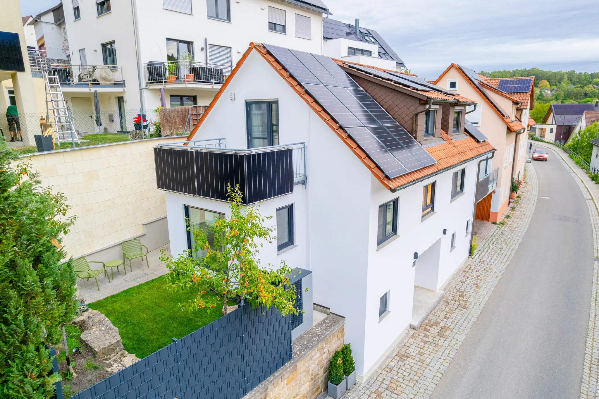 Luftbild eines Hauses am Hang mit Photovoltaikdach in Grafenau