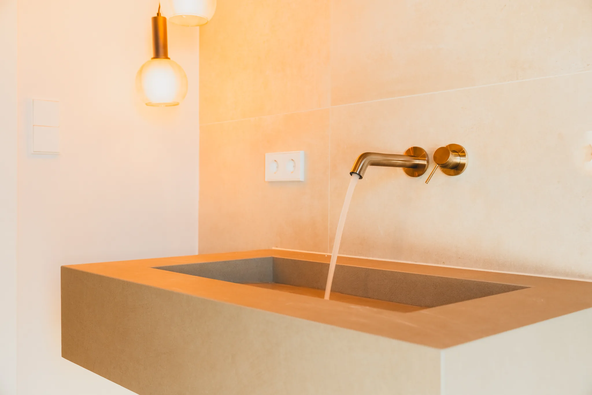 Waschtisch mit Messingarmatur und warmer Wandleuchte – Leutenbach